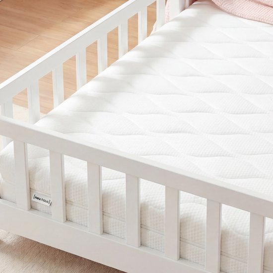 Wit matras met ruitpatroon in een wit bed met huisjesdak.