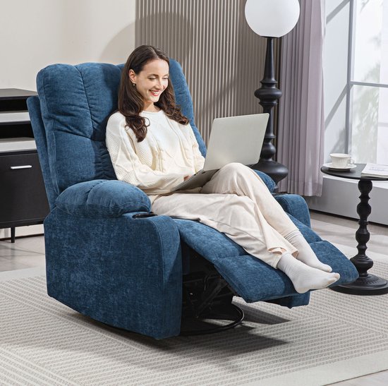 Een vrouw met een witte trui zit ontspannen in een blauwe fauteuil met een laptop op schoot.