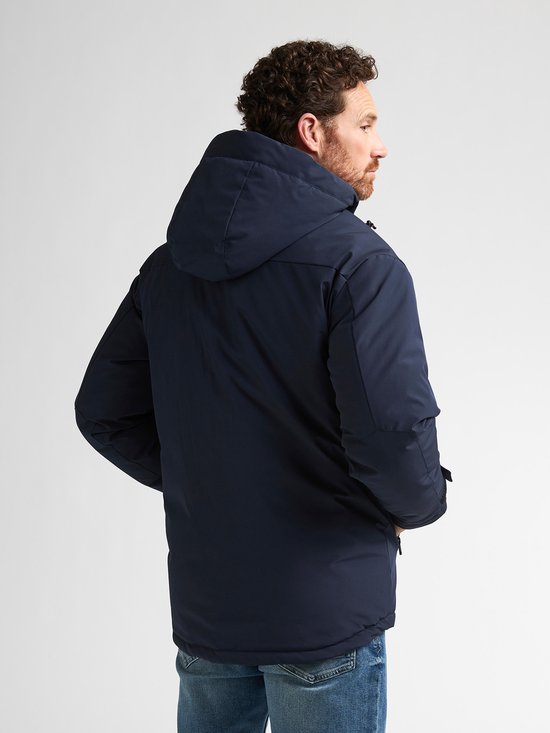 Man draagt donkerblauwe winterjas met capuchon, bekeken vanaf de achterkant.