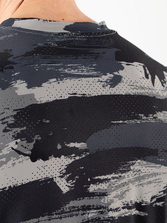 Close-up van de schouder en rug van een man in een grijs en zwart camouflage sportshirt met perforaties.