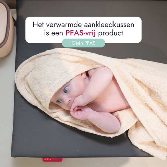 Baby gewikkeld in een zachte, beige handdoek. Het verwarmde aankleedkussen is PFAS-vrij.