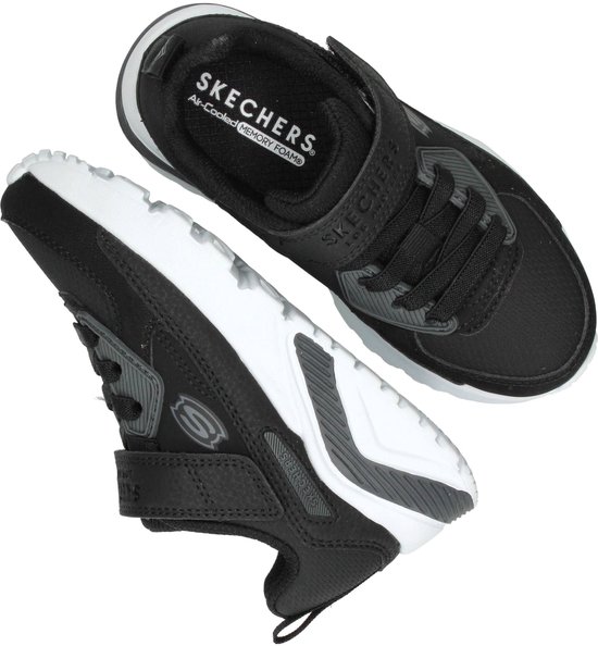 Boven- en zijaanzicht van zwarte Skechers sneakers met klittenband. Witte zolen met grijze details. 'Skechers Air-Cooled Memory Foam' op binnenzool.
