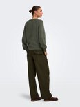 Vrouw in donkergroene trui met broek met cargo zakken, rug en zijkant zichtbaar.