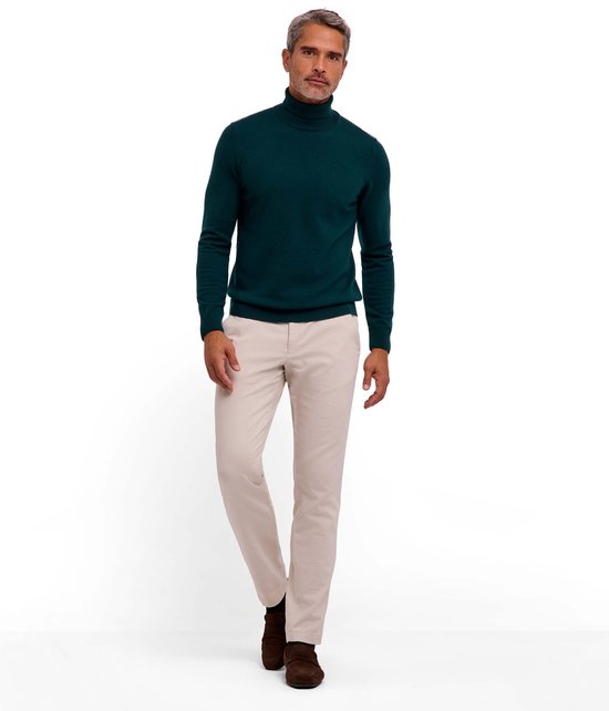 Man in een donkergroene wollen coltrui met beige broek en bruine schoenen.