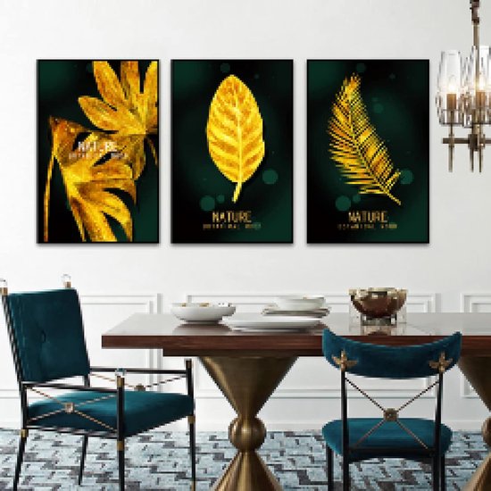 Drie ingelijste gouden botanische kunstwerken boven een eettafel met blauwe fluwelen stoelen.