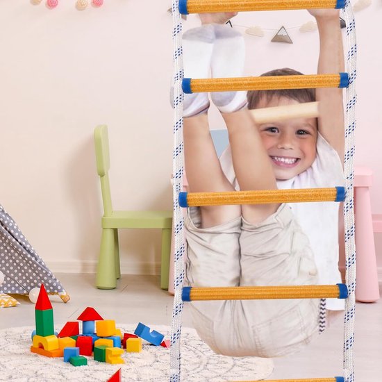 Een lachende jongen hangt ondersteboven aan een reddingsladder in een kinderkamer met speelgoed.