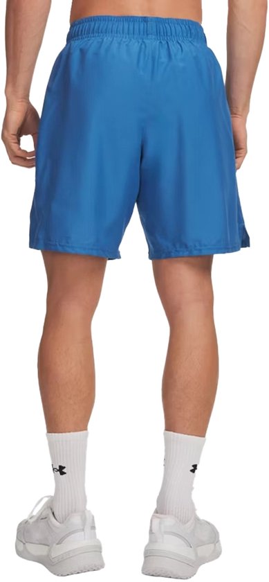 Blauwe sportbroek gedragen door een man, gezien vanaf de achterkant. Hij draagt witte sportsokken en witte sneakers.