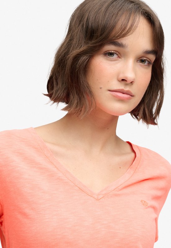 Gros plan sur une mannequin portant un t-shirt Superdry corail à col en V avec logo brodé.