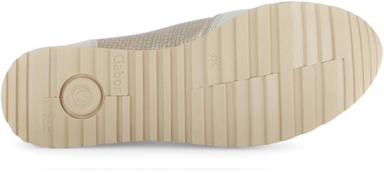 Onderkant van een beige sneaker met profielzool en merklogo.