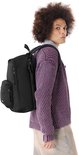 Sac à dos Eastpak noir avec un compartiment pour ordinateur portable, porté par un mannequin aux cheveux bouclés et un pull violet tricoté.