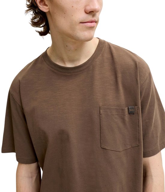 Man draagt een bruin T-shirt met borstzakje en Jack & Jones label.