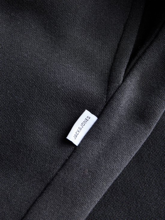 Close-up van zwarte stof met wit label met het JACK&JONES logo.