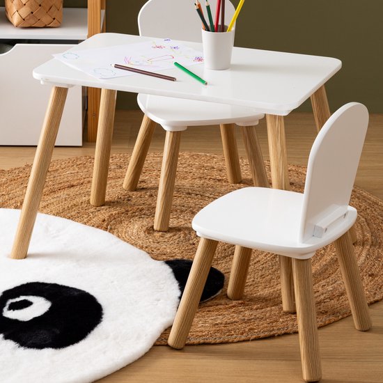 Witte kindertafel met twee witte stoelen, houten poten, op een rond vloerkleed met pandabeer.