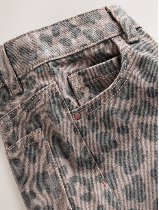 Detailopname van de tailleband, zakken en klinknagels van een taupekleurige jeans met grijs luipaardpatroon.