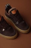 Paar donkerbruine suède sneakers met bontvoering en crèpezool, met logo op de tong.
