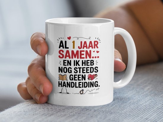Close-up van een hand die een witte mok vasthoudt met tekst over een jubileum.