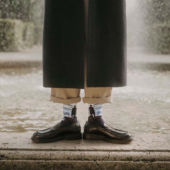 Donkerblauwe sokken met "De Wanderer above the Sea of Fog" van Friedrich, bij water.