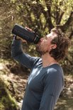 Man met donkerblauw NOMAD drinkfles in de natuur.