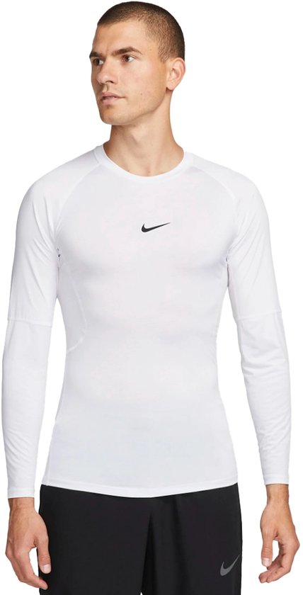 Man draagt wit Nike Pro longsleeve shirt met zwart Nike logo op de borst en zwarte shorts.
