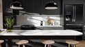Moderne keuken met antracietgrijze kasten, een wit eiland, zwarte apparaten en hanglampen.