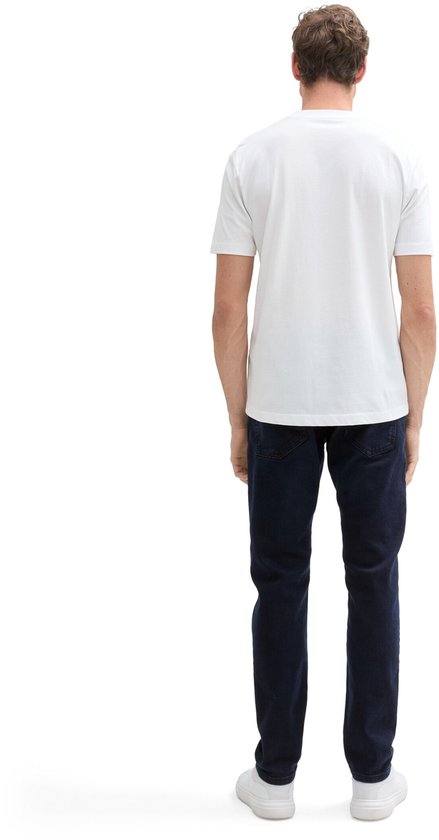 Een man met een witte t-shirt en donkerblauwe jeans, van achteren gezien.