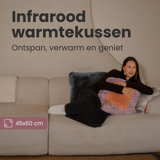 Une femme se détend sur un canapé avec un coussin chauffant rose.