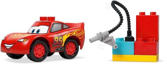 Rode LEGO Duplo Lightning McQueen auto naast een rode, blauwe en gele brandstofpomp met zwarte slang.