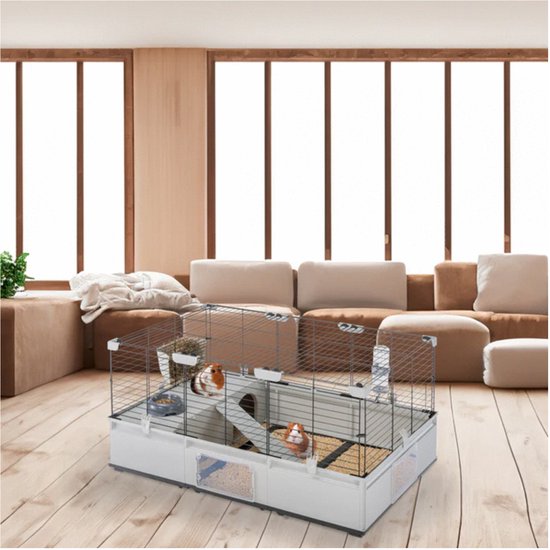Een ruime kooi met wit plastic onderstel,traliewanden en diverse accessoires zoals voerbakjes, huisjes en een loopplank. Twee cavia's zijn in de kooi.