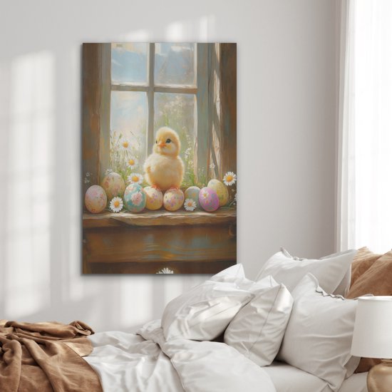 Schilderij van een kuiken en paaseieren op een vensterbank, hangend boven een bed met witte kussens.