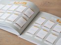 Open schoolfotoboek, lichtgroen met gouden accenten. Pagina's met blanco fotokaders en de tekst 'JAAR' en 'PLAATS HIER DE PASFOTO'.