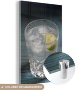MuchoWow® Glasschilderij 60x90 cm - Schilderij acrylglas - Een Gin tonic op een blauwe tafel - Foto op glas - Schilderijen