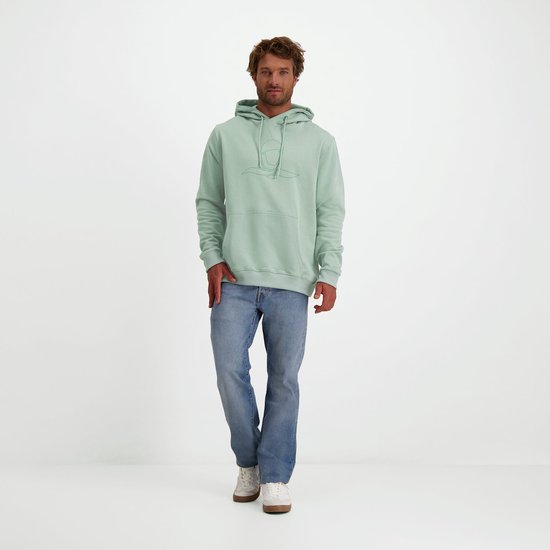 Staande man in mintgroene hoodie met logo en jeans op een witte achtergrond.