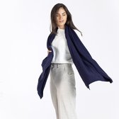 Vrouw in witte trui en grijze broek, met een donkerblauwe sjaal om haar nek geslagen.