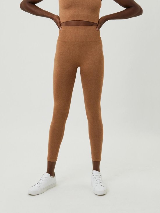 Vooraanzicht van een vrouw in bruine, gemêleerde naadloze legging met geribbelde tailleband en witte sneakers.
