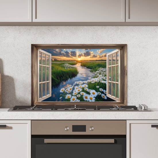 Een keuken met een spatscherm van een open raam met uitzicht op een zonsondergang.