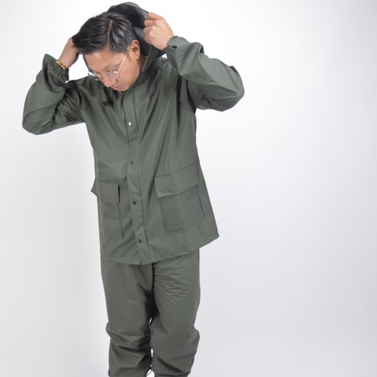 Man trekt groene Hydrowear regenjas met capuchon en bijpassende broek aan.