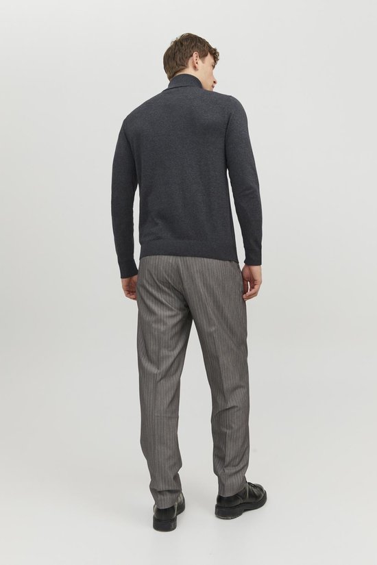 Man met de rug naar de camera, draagt een donkergrijze coltrui en een grijze pantalon met krijtstrepen.