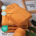 Stapel okergele handdoeken (50x100 cm) met een textuur van 500 g/m2. Wasbaar tot 60°C. OEKO-TEX gecertificeerd.