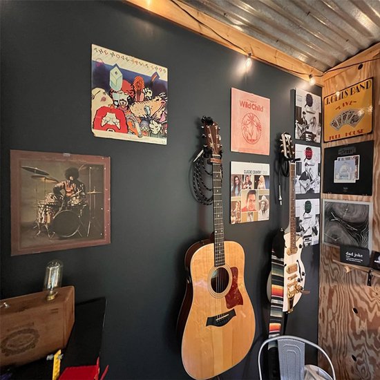 Muziekhoek met gitaren en aan de muur gemonteerde platen en posters.