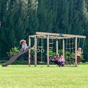 Houten klimtoestel met kinderen, glijbaan, schommel en klimnet.