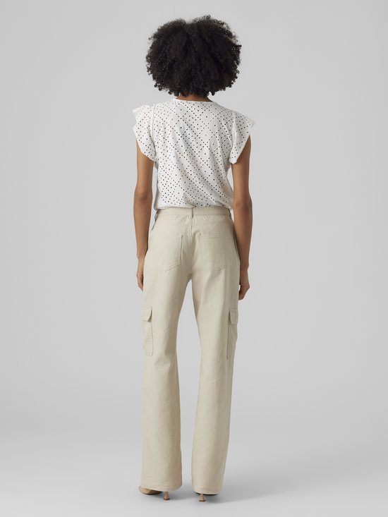 Femme portant un haut blanc court à volants et détails ajourés, et un pantalon cargo beige. Le dos est montré.