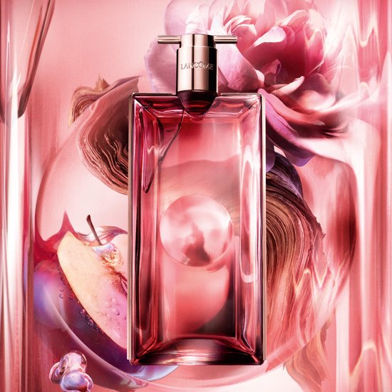Lichtroze Lancôme Idôle parfumfles omringd door roze bloemblaadjes en een gesneden appel.