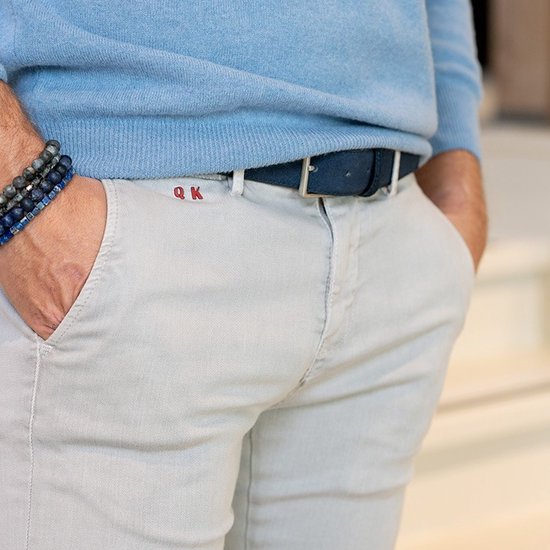 Gros plan sur un homme portant un pull bleu clair, un chino beige et une ceinture en daim bleu.