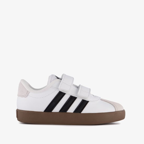 Wit leren Adidas sneakers met klittenbandsluiting, zwarte strepen en bruine zool.