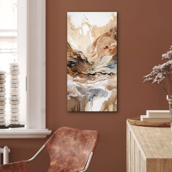 Peinture abstraite aux tons beige, brun et gris, suspendue au-dessus d'un fauteuil en cuir.