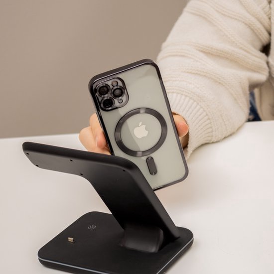 Hand toont transparant telefoonhoesje met MagSafe-ring op een zwarte draadloze oplader.