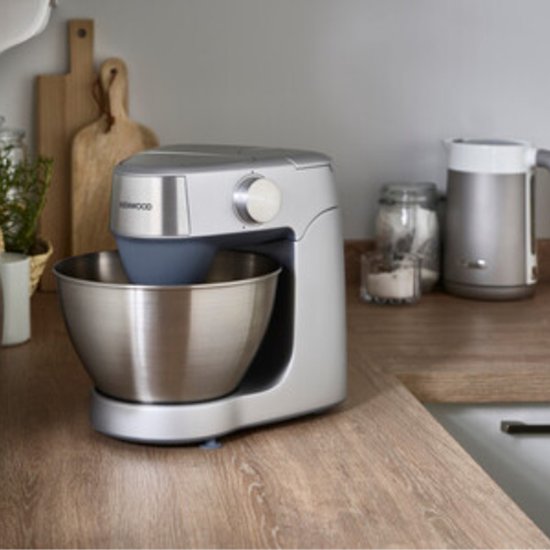 Zilverkleurige Kenwood keukenmachine met metalen kom op een aanrecht.