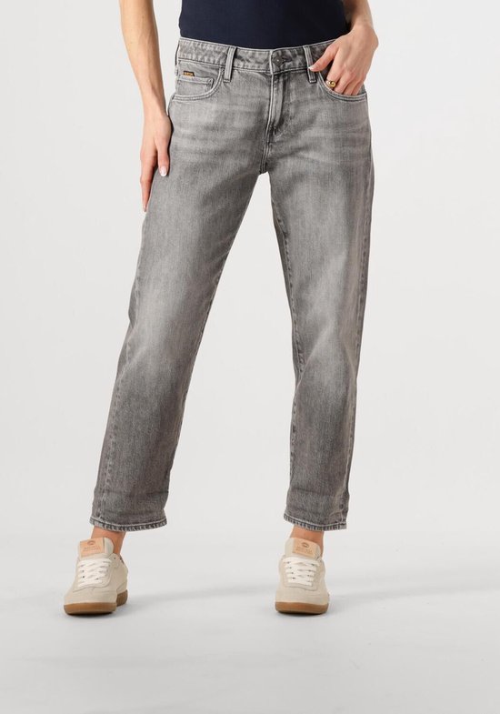 Model van voren in een lichtgrijze jeans met opgerolde zoom en beige sneakers.