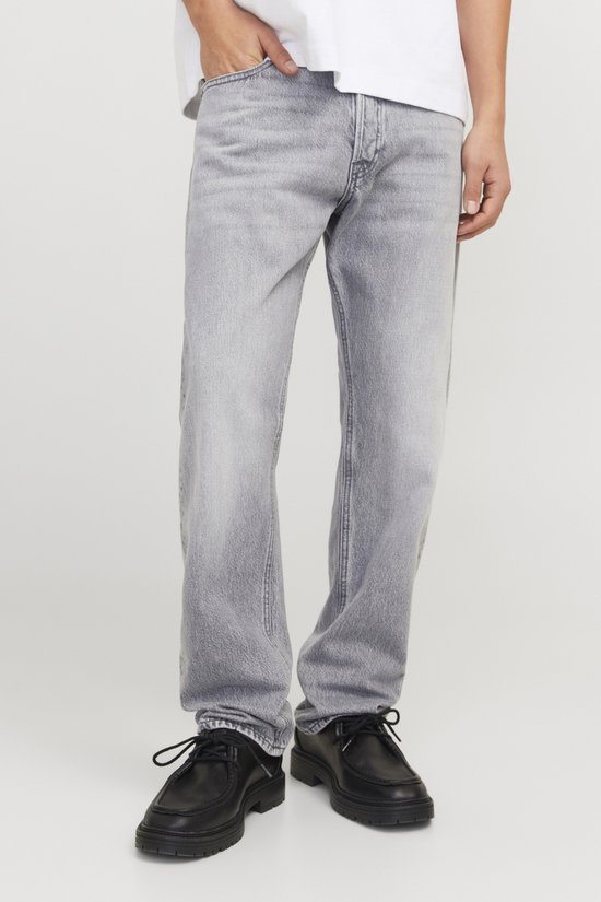 Grijze jeans, getoond op een model met zwarte schoenen.