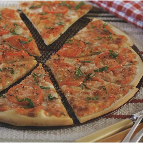 Margherita pizza in punten gesneden op een rooster, met tomaten en basilicum.
